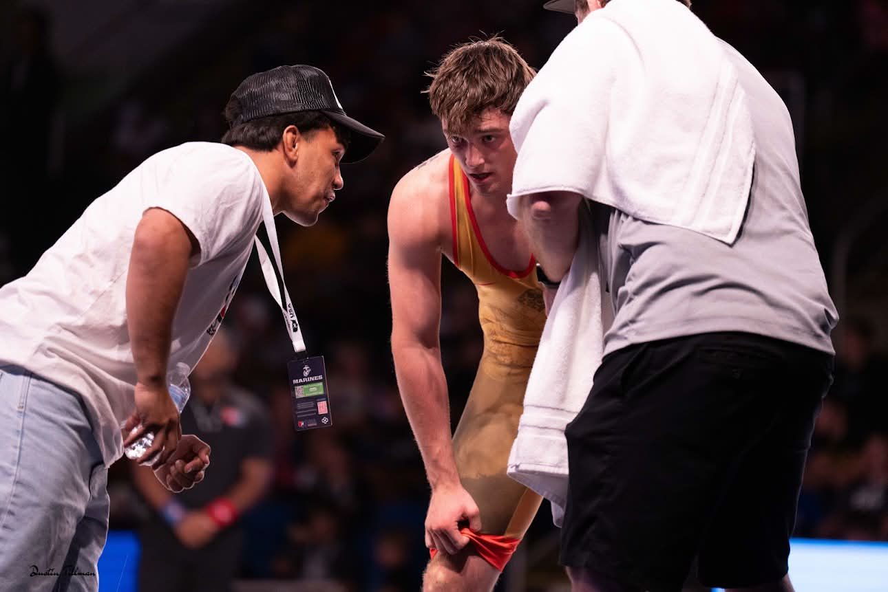 Coach Peyton Omania coaching a wrestler from the corner